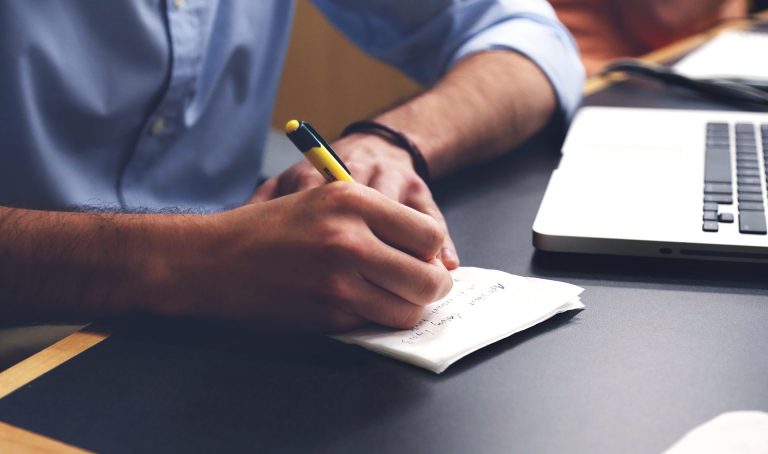 A person writing on paper with a pen.