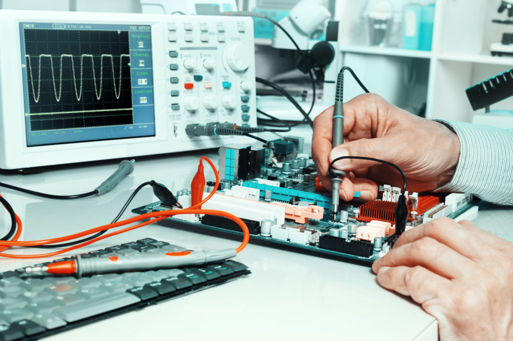 A person working on electronics in front of a computer.