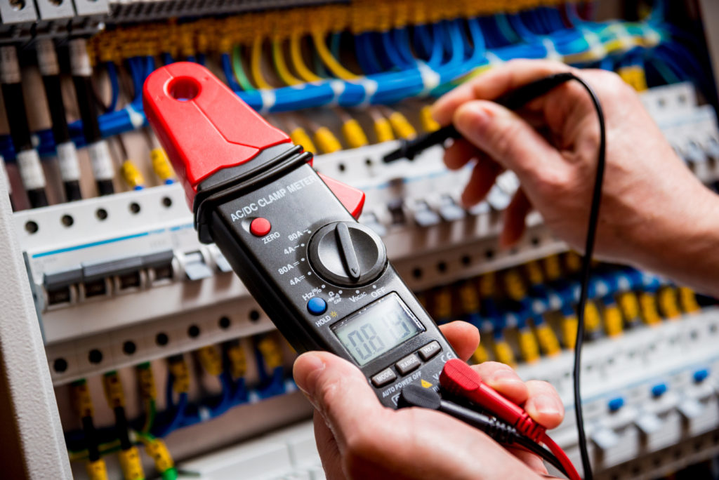 A person holding a multimeter in their hand.