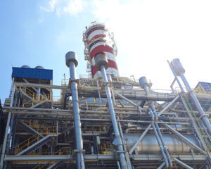 A large industrial plant with pipes and a tower.