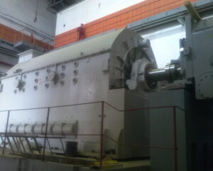 A large machine in a factory room with brick walls.