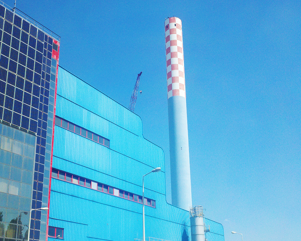 A large blue building with a tall white and red chimney.