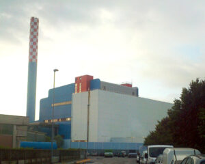A large factory with cars parked on the side of it.
