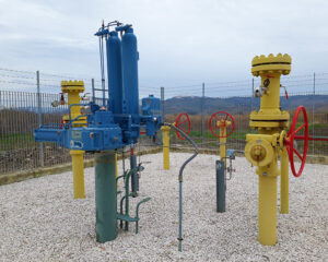 A group of yellow and blue pipes sitting on top of gravel.